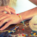 Woman hands making a bracelet with a rope and colorful beads, DIY fashion