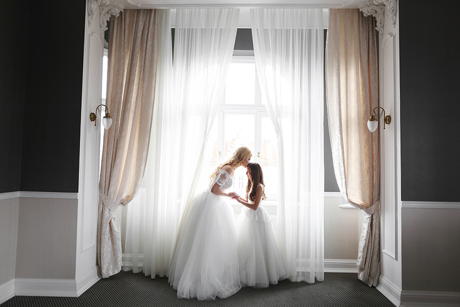 Bride and flower girl bridesmaid by window