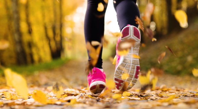 Close up of runner’s feet running in autumn leaves training exercise pink sneakers