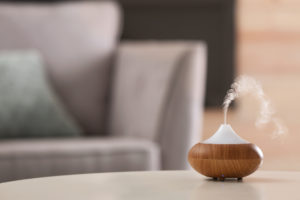Aroma essential oil diffuser lamp on table against blurred background