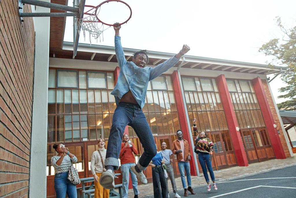 young man dunks hanging off hoop basketball