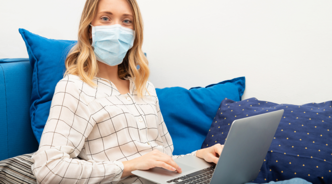 lady in facemask using computer