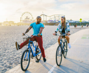 Young-Black man blonde woman couple-riding-bikes-in-Santa-Monica
