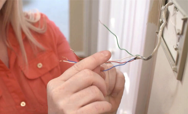 woman installing thermostat electrical wiring