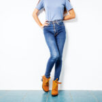 Young girl blue jeans brown shoes wall white.