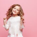 beautiful little girl in dress standing and posing over white background