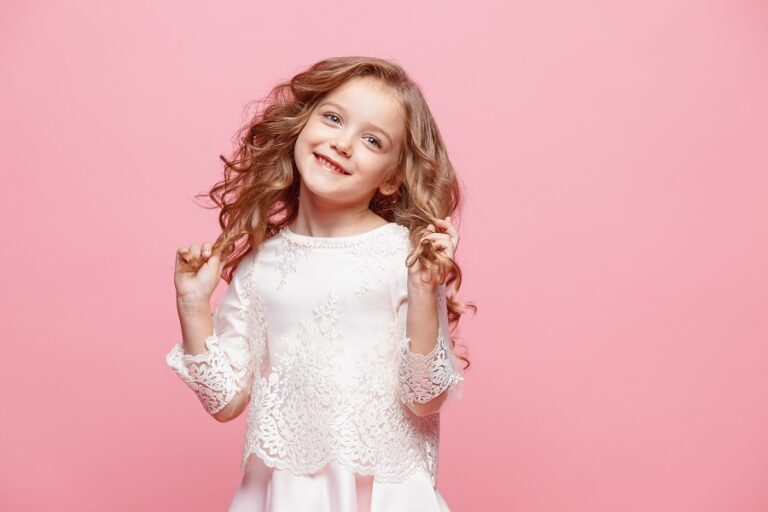 beautiful little girl in dress standing and posing over white background